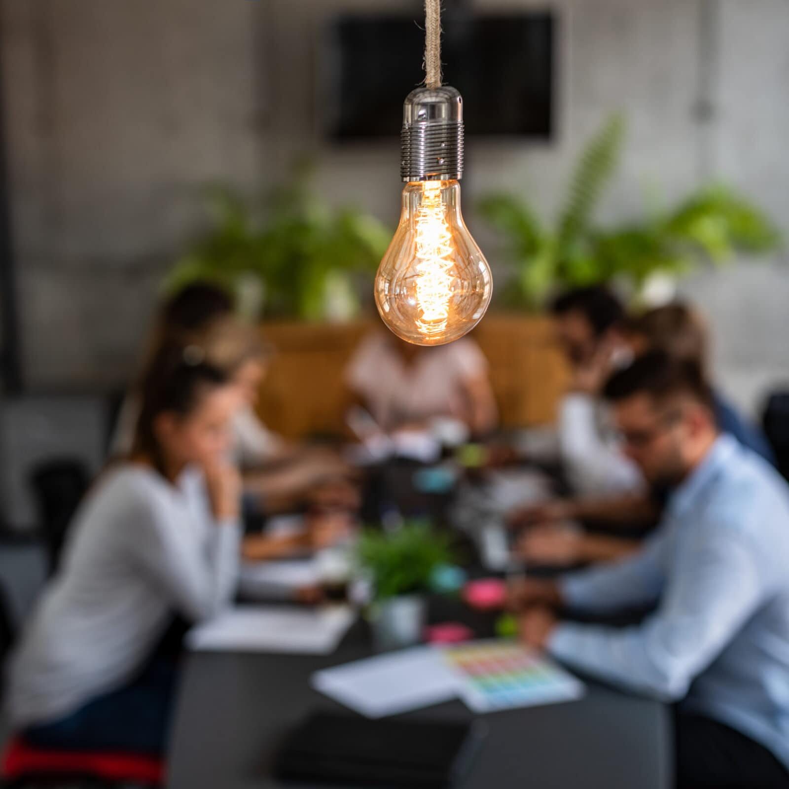 Young business people are discussing together a new startup project. A glowing light bulb as a new idea.