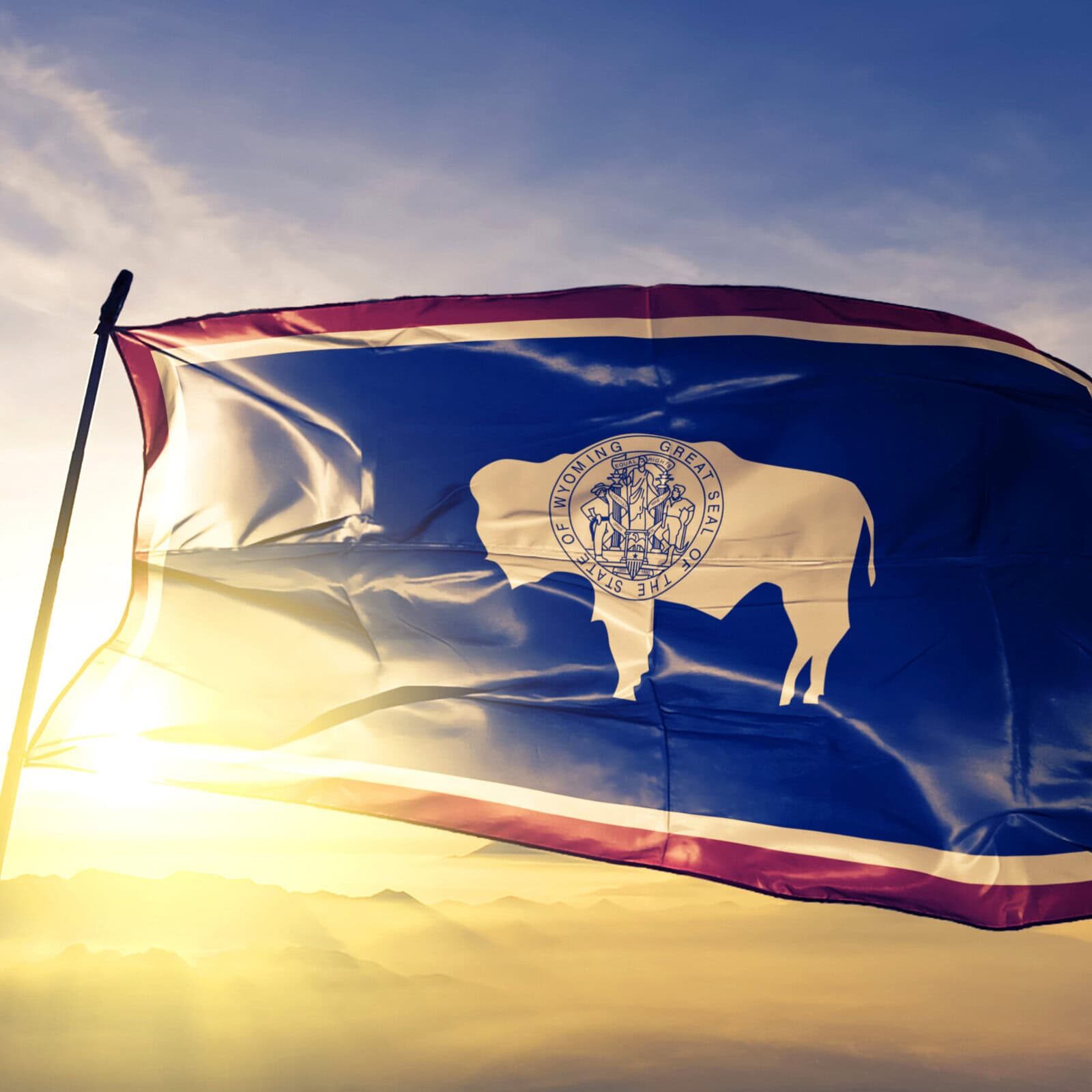 Wyoming state of United States flag textile cloth fabric waving on the top sunrise mist fog