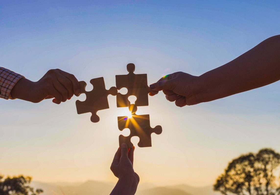 Human hands holding jigsaw puzzle at sunset background.team work and success and strategy concept.