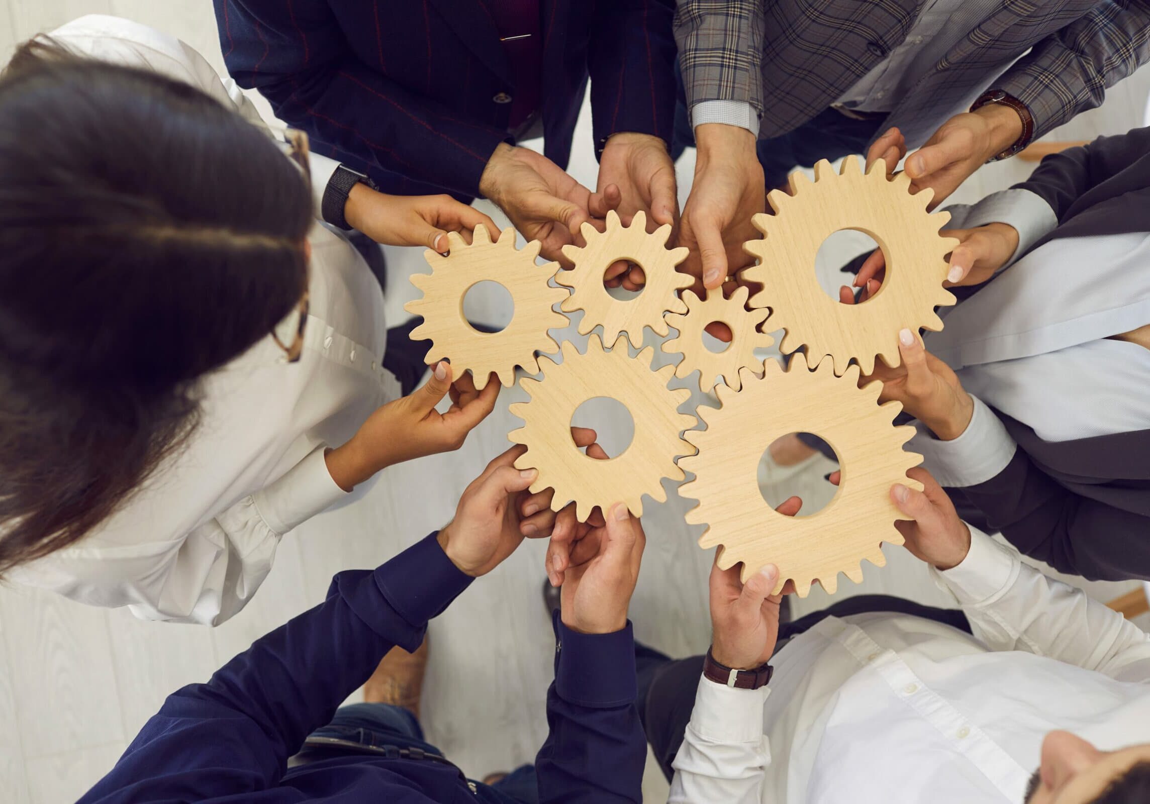 Business team people hands holding gear wheels shot with view from above