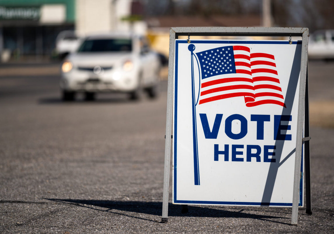 A Vote Here sign in a parking lot. High quality photo