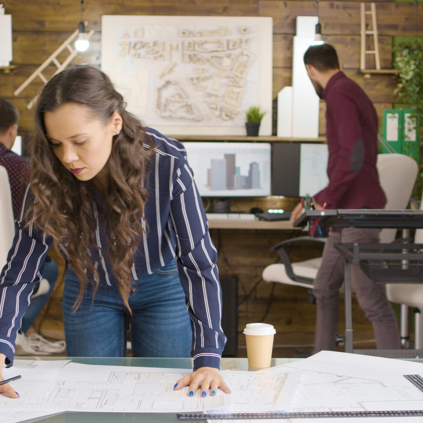 Beautiful caucasian designer working on blueprints in modern cozy office